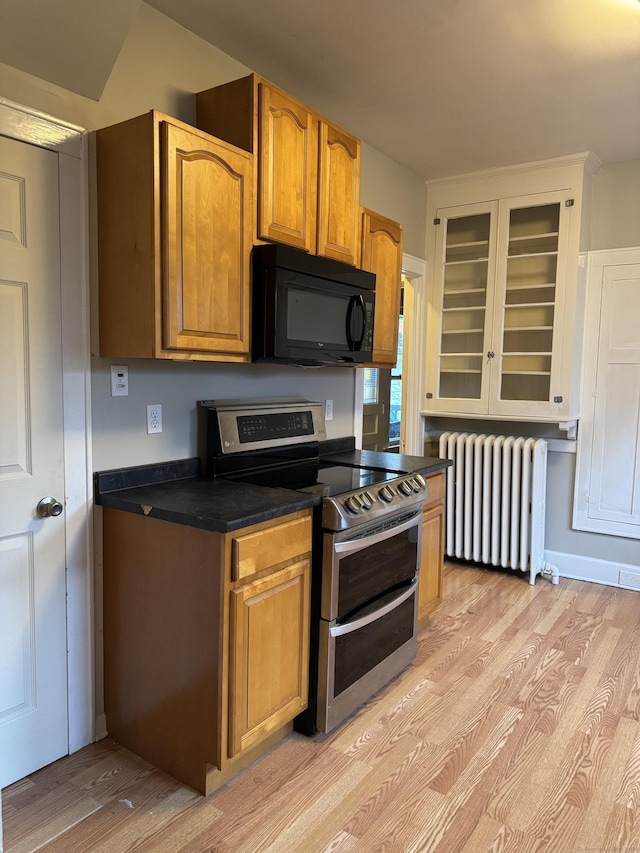 kitchen with light hardwood / wood-style floors, range with two ovens, and radiator heating unit