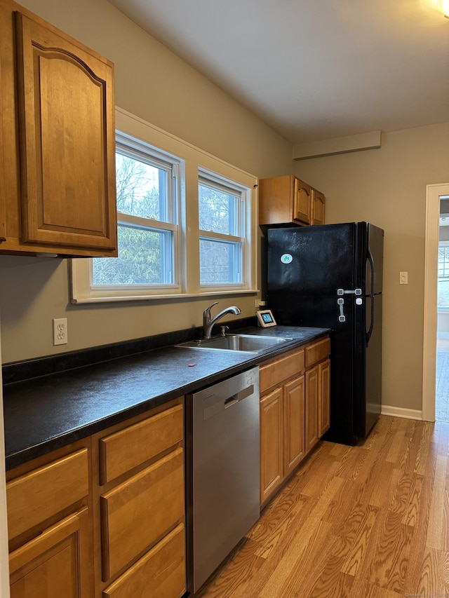 kitchen with black fridge, light wood-type flooring, stainless steel dishwasher, and sink