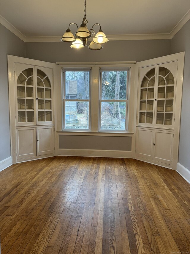 unfurnished dining area with hardwood / wood-style floors, an inviting chandelier, and crown molding