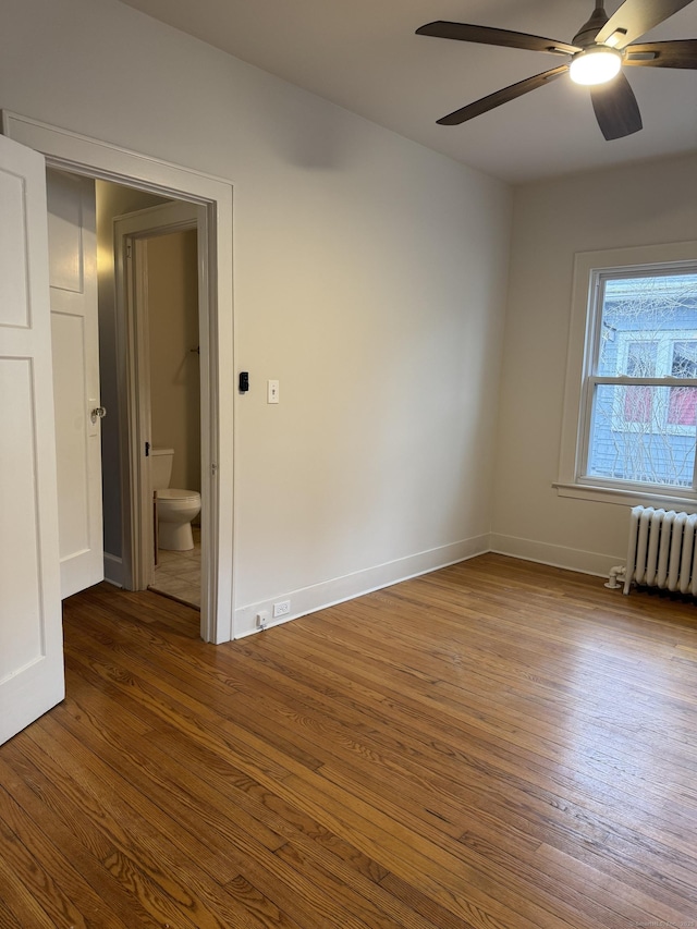 spare room with ceiling fan, wood-type flooring, and radiator