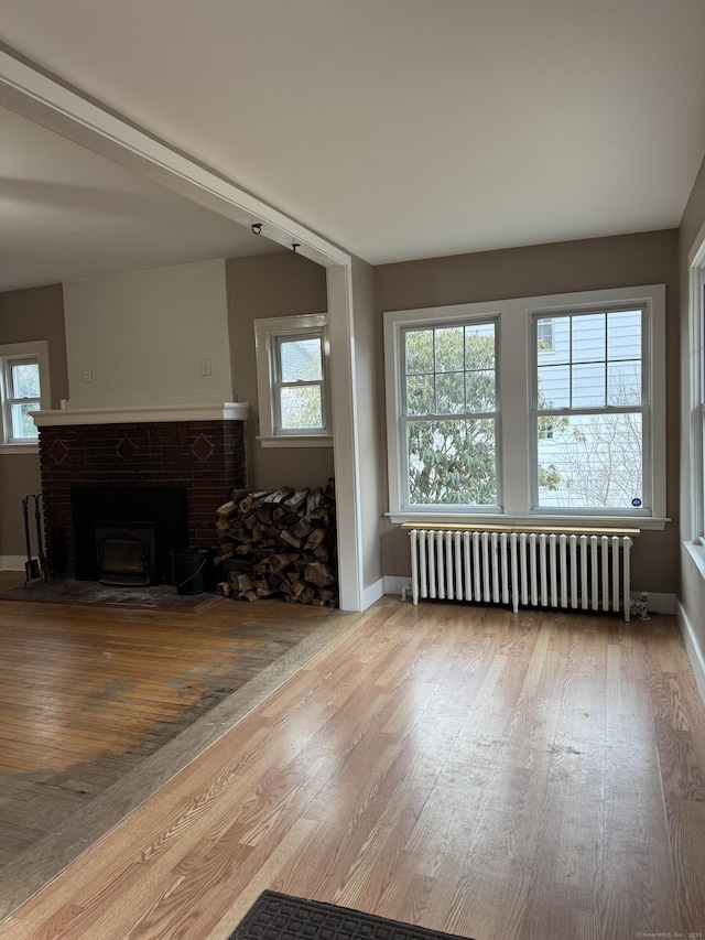 unfurnished living room featuring a wealth of natural light, light hardwood / wood-style flooring, and radiator