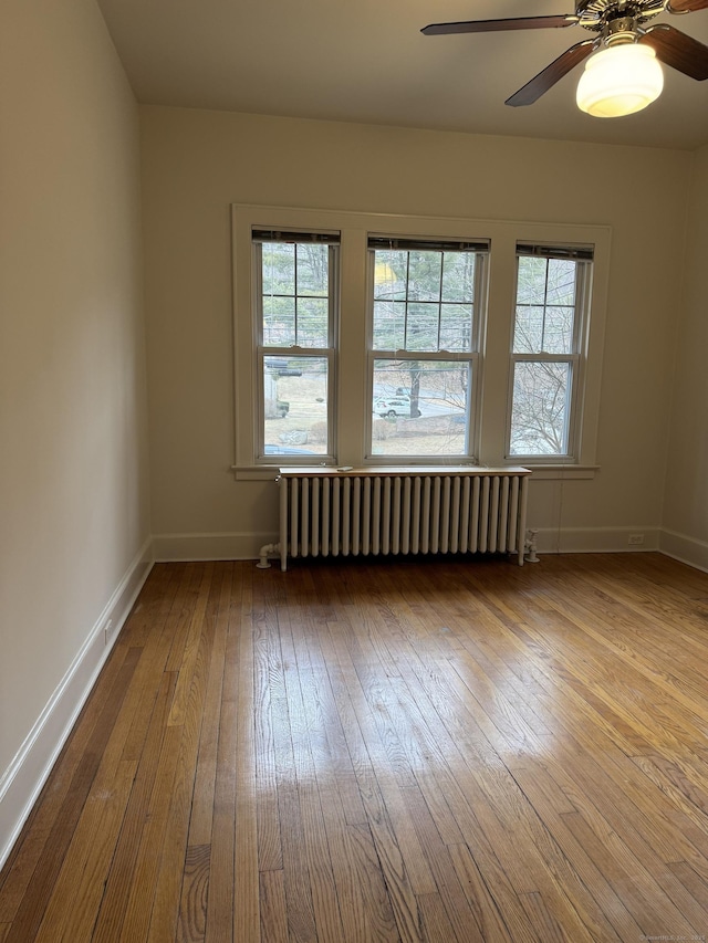 empty room with radiator, ceiling fan, and light hardwood / wood-style flooring