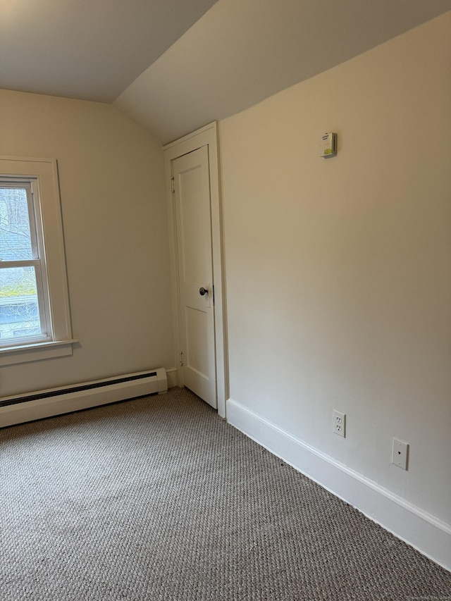 empty room featuring carpet, baseboard heating, and vaulted ceiling