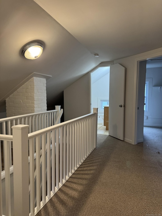 hallway with carpet flooring and vaulted ceiling