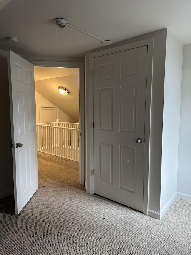 hallway featuring carpet floors and lofted ceiling