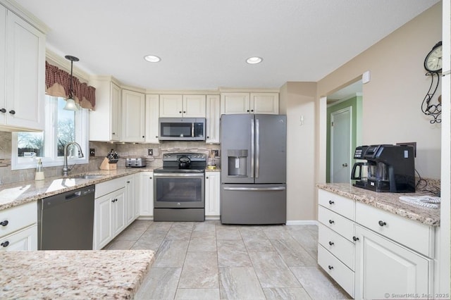 kitchen with light stone countertops, backsplash, stainless steel appliances, sink, and pendant lighting