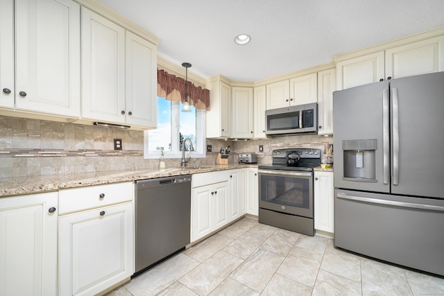 kitchen with light stone countertops, sink, backsplash, pendant lighting, and appliances with stainless steel finishes