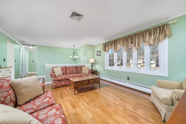 living room featuring baseboard heating, hardwood / wood-style flooring, crown molding, and an inviting chandelier