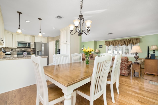 dining area with light hardwood / wood-style flooring and a chandelier