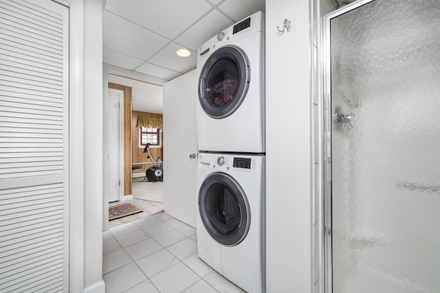 laundry area with light tile patterned flooring and stacked washing maching and dryer