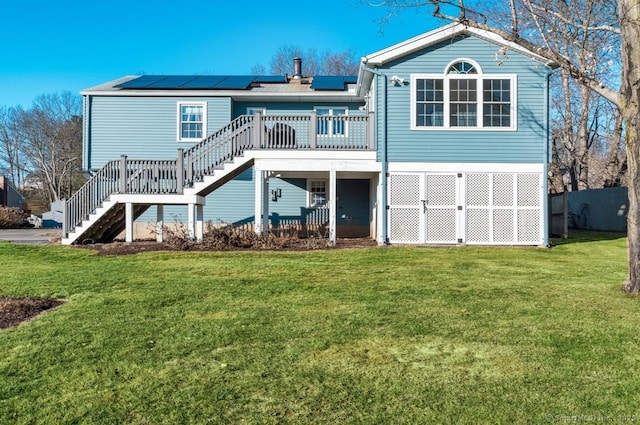 back of house featuring a wooden deck, a yard, and solar panels