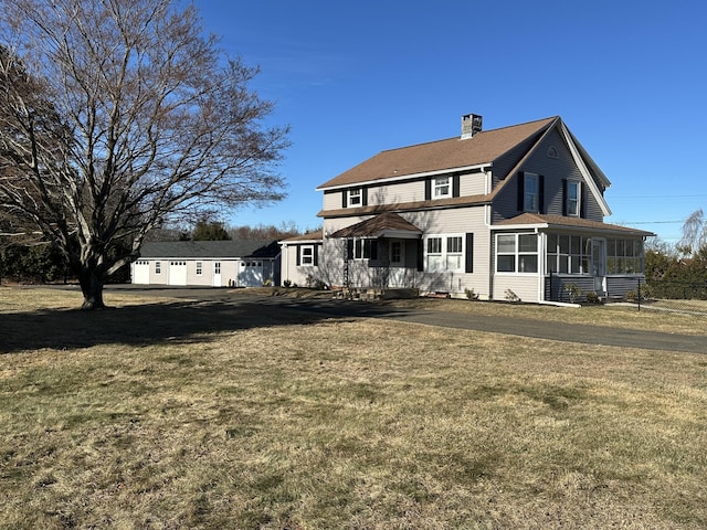 rear view of property featuring a lawn and a sunroom