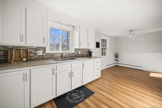 kitchen featuring sink, white cabinetry, ceiling fan, light hardwood / wood-style floors, and a baseboard radiator