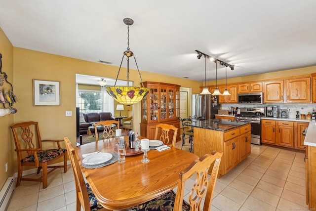 kitchen featuring light tile patterned floors, a baseboard radiator, a kitchen island, pendant lighting, and stainless steel appliances