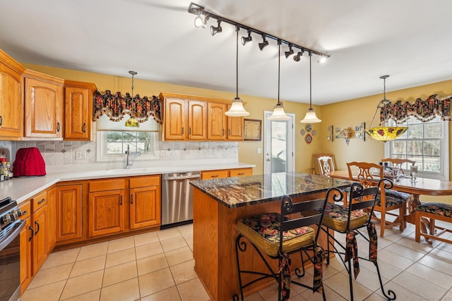 kitchen with a kitchen island, appliances with stainless steel finishes, decorative light fixtures, sink, and a kitchen bar