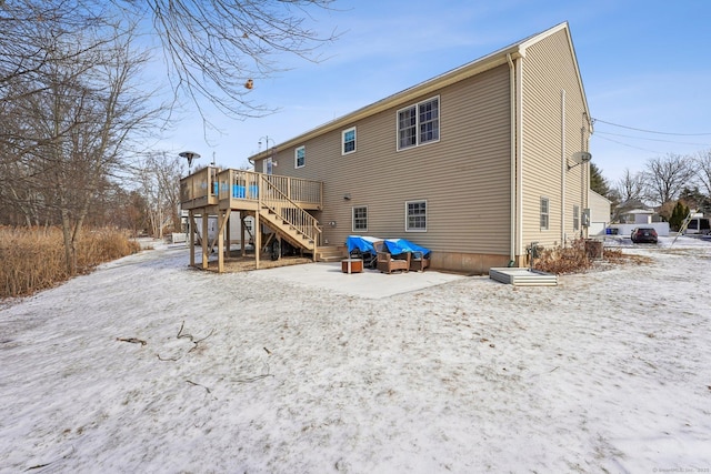 snow covered rear of property with a deck