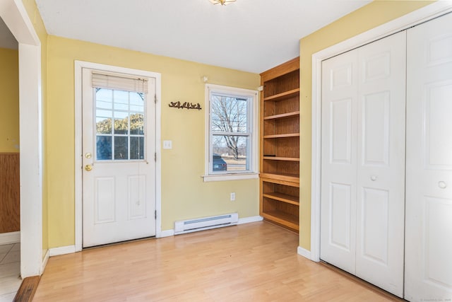 foyer featuring baseboard heating, light wood-type flooring, and a healthy amount of sunlight