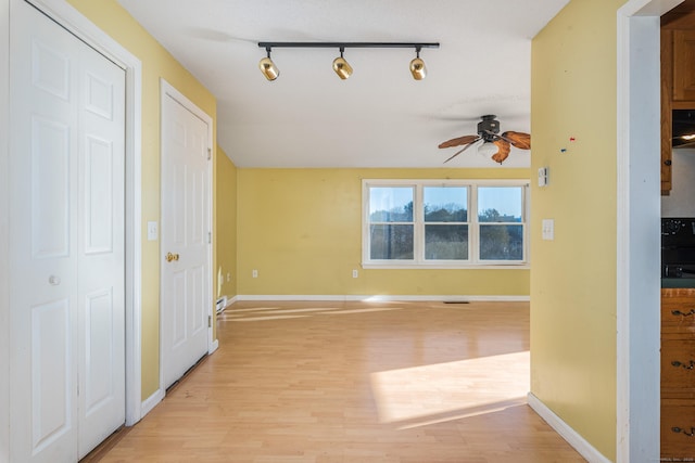 interior space featuring ceiling fan, track lighting, and light hardwood / wood-style flooring