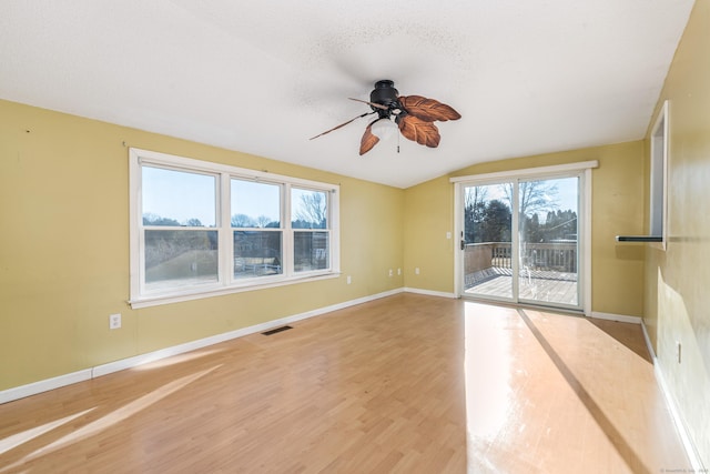 spare room with ceiling fan, vaulted ceiling, a textured ceiling, and hardwood / wood-style floors