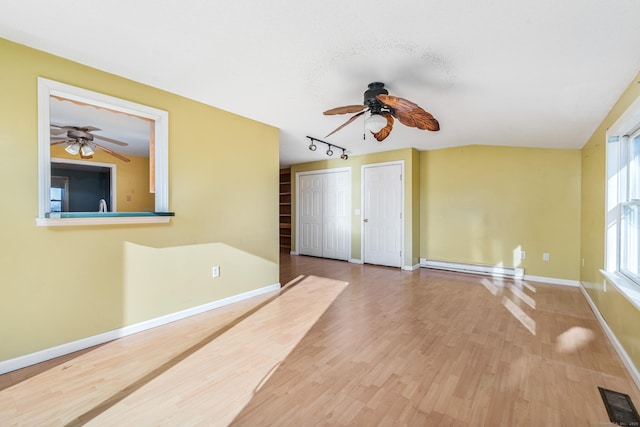 unfurnished room featuring a baseboard heating unit, rail lighting, and hardwood / wood-style floors