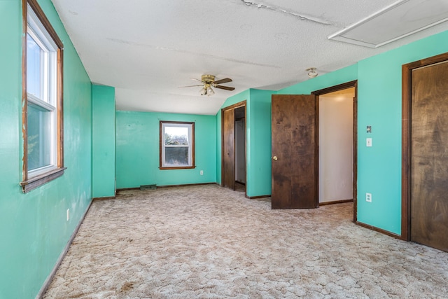 carpeted spare room with ceiling fan, a textured ceiling, and lofted ceiling