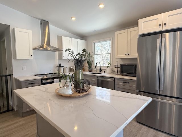 kitchen with white cabinetry, wall chimney range hood, stainless steel appliances, and a kitchen island