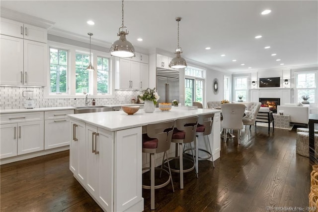 kitchen with sink, decorative light fixtures, white cabinetry, a kitchen island, and built in fridge