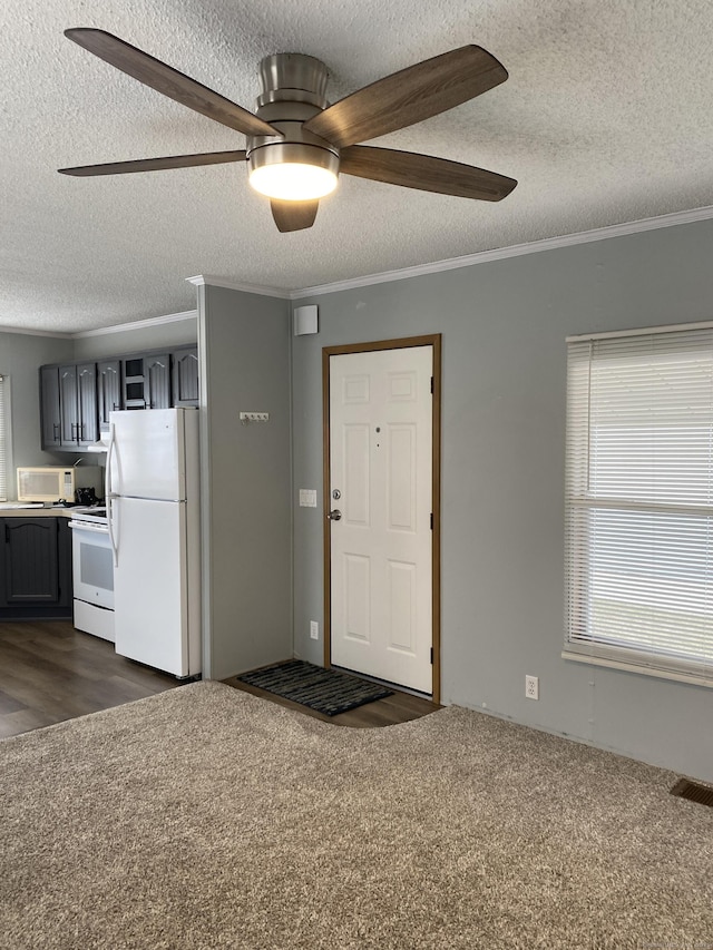 foyer entrance with crown molding, ceiling fan, a textured ceiling, and dark colored carpet