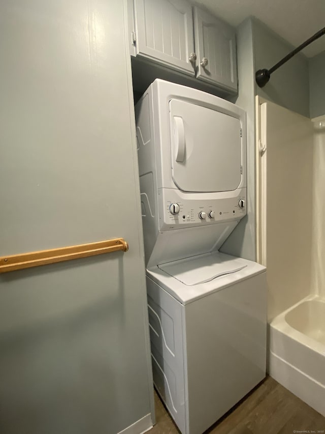 laundry room featuring stacked washer and dryer and dark wood-type flooring