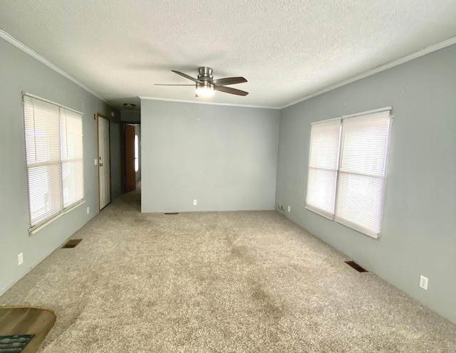 unfurnished room with ceiling fan, ornamental molding, carpet floors, and a textured ceiling