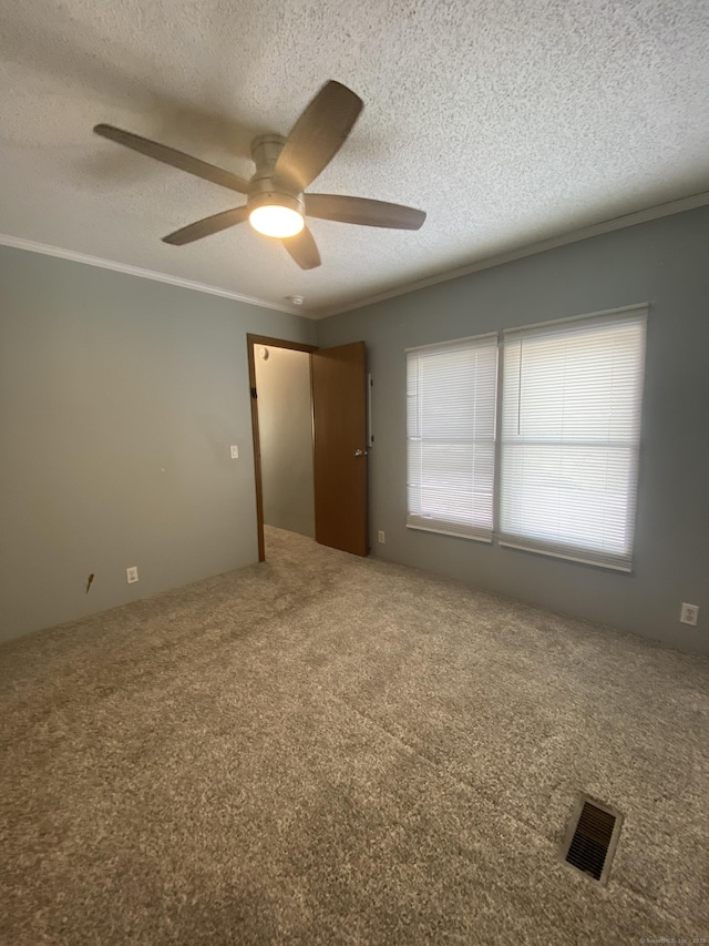 spare room featuring ceiling fan, ornamental molding, a textured ceiling, and carpet flooring