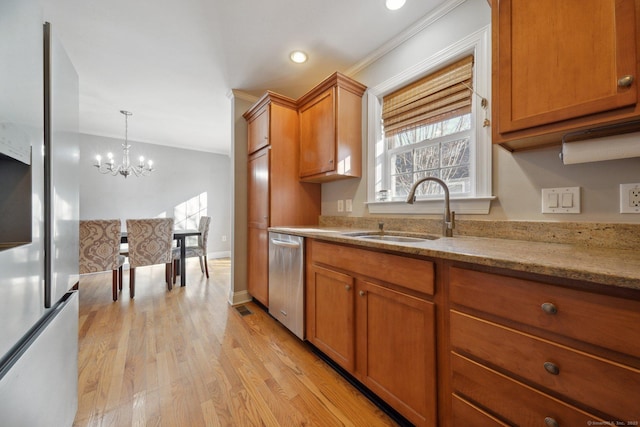 kitchen featuring sink, light hardwood / wood-style floors, light stone countertops, a chandelier, and appliances with stainless steel finishes