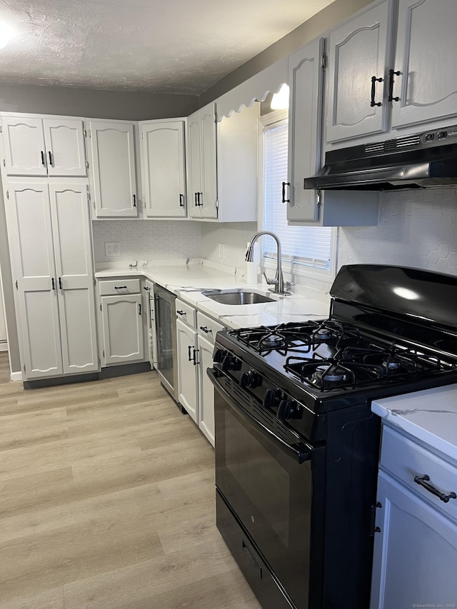 kitchen with gas stove, sink, light hardwood / wood-style flooring, a textured ceiling, and white cabinets