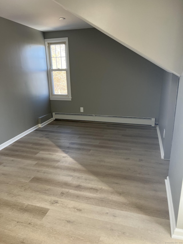 bonus room featuring wood-type flooring and a baseboard heating unit