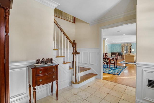 stairs featuring a wainscoted wall, tile patterned flooring, a decorative wall, and crown molding