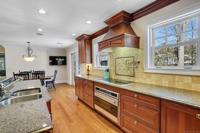 kitchen with ornamental molding, oven, black electric stovetop, light wood-style floors, and a sink