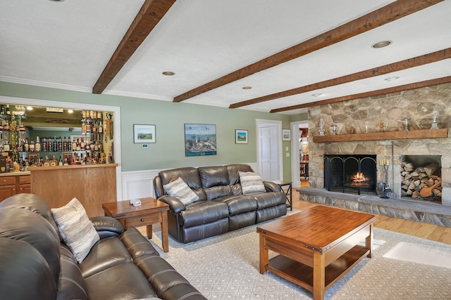 living room featuring a wainscoted wall, a fireplace, wood finished floors, beam ceiling, and a bar