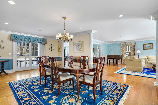 dining area with a chandelier, a wainscoted wall, wood finished floors, ornate columns, and crown molding