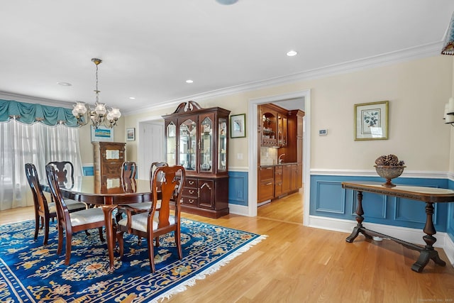 dining room featuring a notable chandelier, light wood finished floors, recessed lighting, ornamental molding, and wainscoting