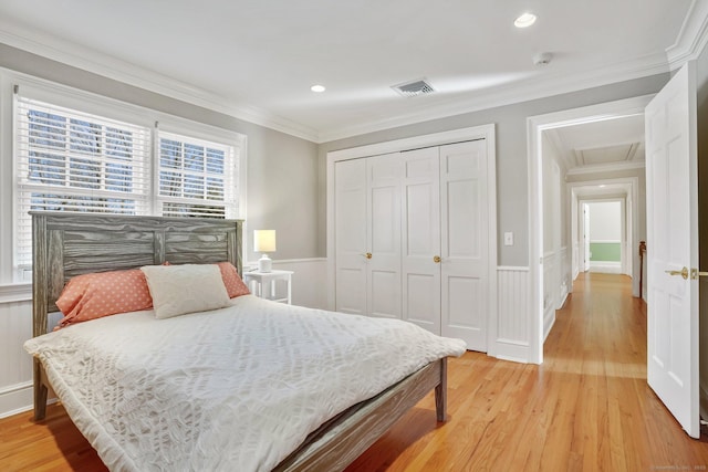 bedroom featuring ornamental molding, a closet, a wainscoted wall, and light wood-style floors