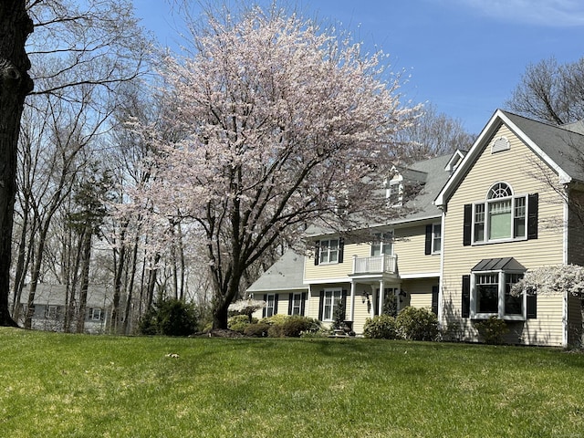 view of front facade featuring a front lawn and a balcony