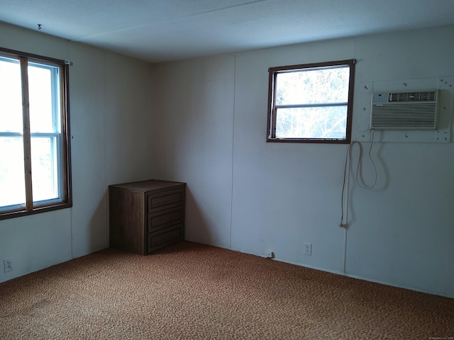 carpeted spare room featuring an AC wall unit