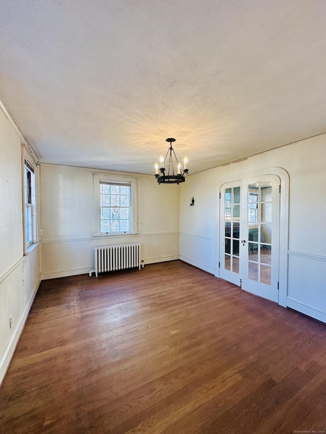 unfurnished room featuring a textured ceiling, french doors, radiator, dark hardwood / wood-style flooring, and a chandelier