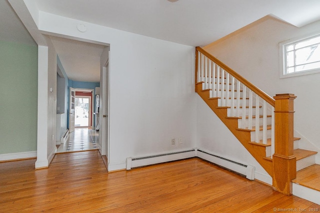 staircase featuring hardwood / wood-style flooring, a wealth of natural light, and a baseboard radiator