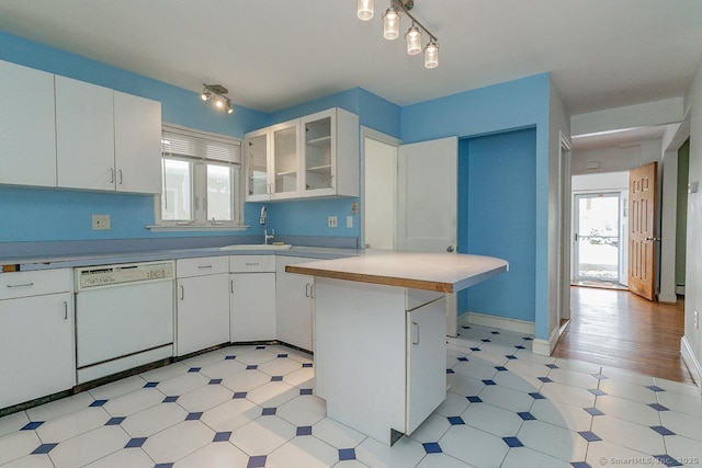 kitchen with a kitchen bar, track lighting, dishwasher, kitchen peninsula, and white cabinets