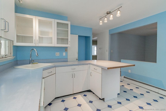 kitchen with white cabinetry, sink, baseboard heating, kitchen peninsula, and track lighting