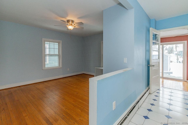 unfurnished room with baseboard heating, ceiling fan, radiator, and light hardwood / wood-style floors