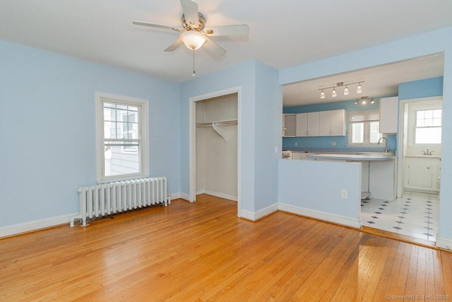 unfurnished bedroom featuring sink, radiator heating unit, light hardwood / wood-style floors, and a closet