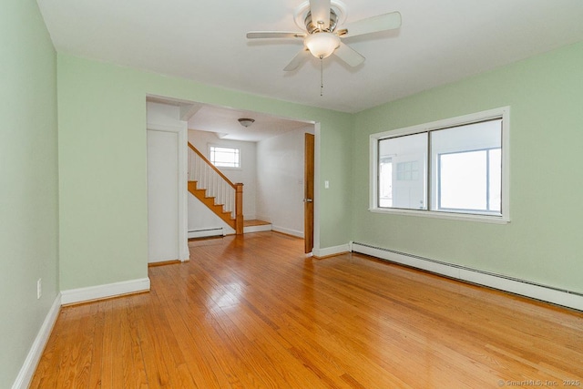 unfurnished room featuring ceiling fan, a baseboard heating unit, and light wood-type flooring