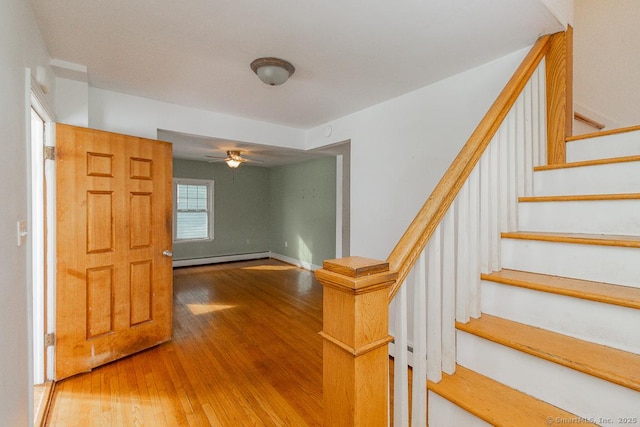 stairs with hardwood / wood-style flooring, a baseboard radiator, and ceiling fan